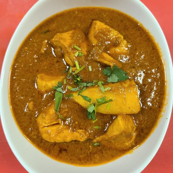 New Little India's chicken curry, a rich orange-brown dish with chicken pieces and cilantro.